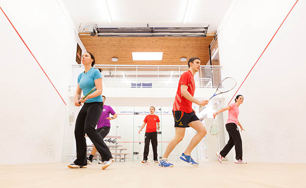 People participating in Squash 101 on a squash court